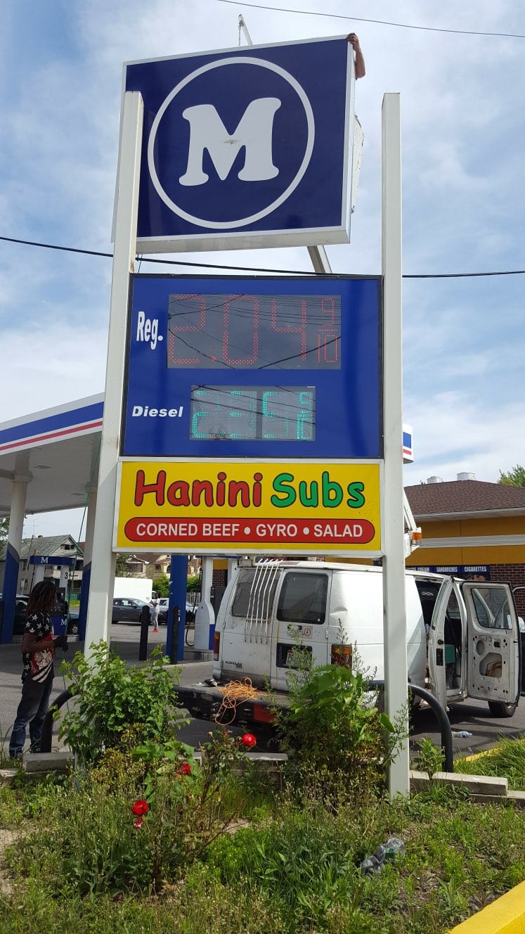 Pylon sign with an illuminated M cabinet, LED fuel price digits and a Hanini Subs panel