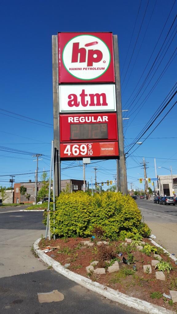 Red hp Hanini Petroleum pylon sign with atm and regular fuel price panels against blue sky
