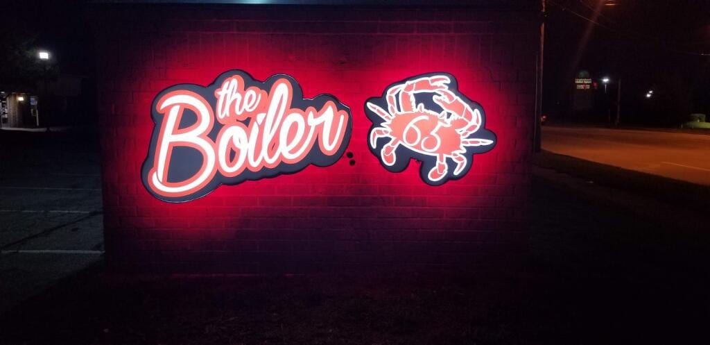Illuminated the Boiler logo sign and crab cabinet glowing red on a brick wall at night