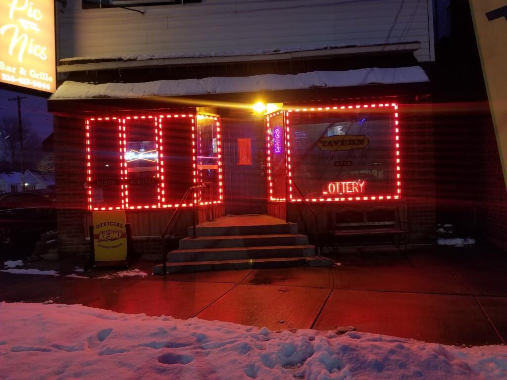 Pic Nics Bar & Grille storefront windows outlined in red LED tube lighting at night in snow