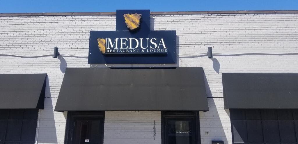 Medusa Restaurant & Lounge cabinet sign mounted above awnings on a white brick building