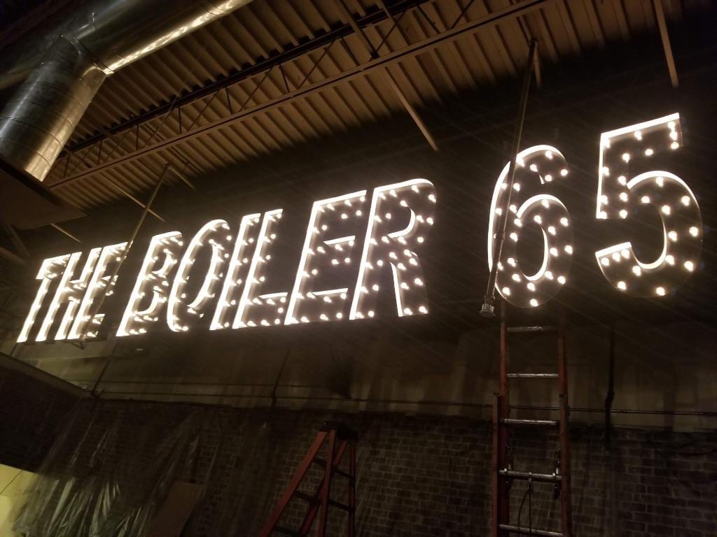 Exposed-bulb THE BOILER 65 marquee letters mounted high on an interior wall