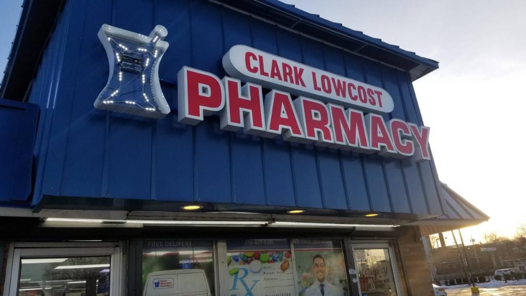 Clark Lowcost Pharmacy channel letters and mortar-and-pestle logo on a blue metal building