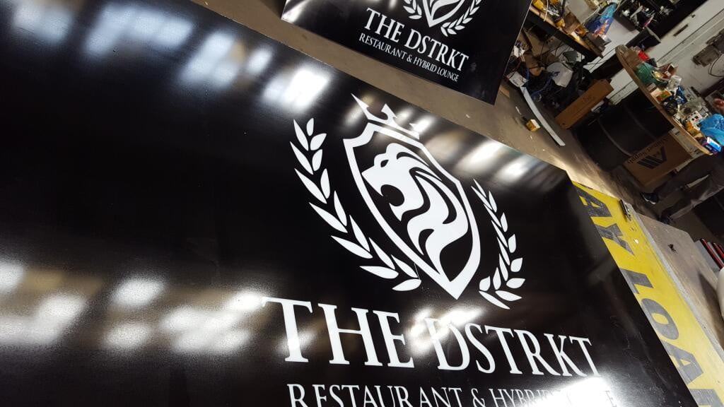 Printed black panels with The Dstrkt lion crest logo lying on the shop floor