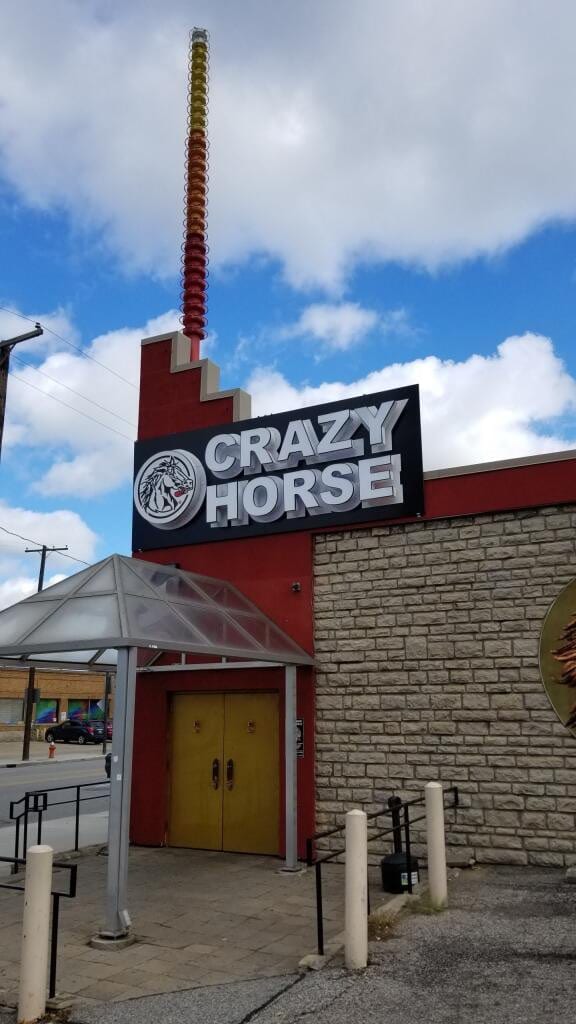 Crazy Horse cabinet sign with a horse logo above a red and stone building entrance