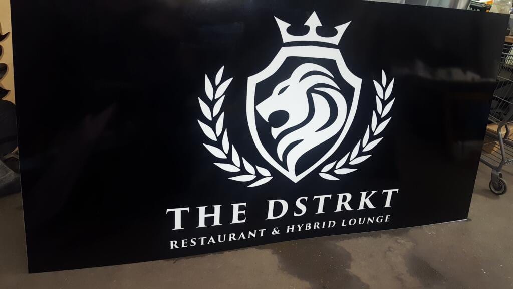 Printed black panel with The Dstrkt lion crest logo standing inside the shop