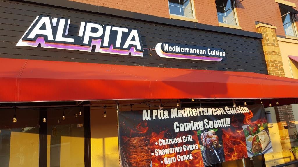 AL PITA Mediterranean Cuisine lit letters on a black fascia above a red awning and printed banner