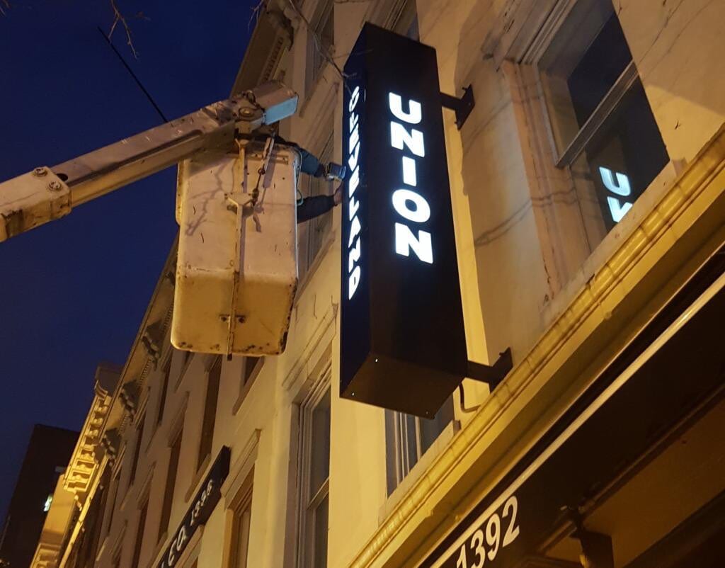 Illuminated CLEVELAND UNION blade cabinet sign projecting from a building at dusk