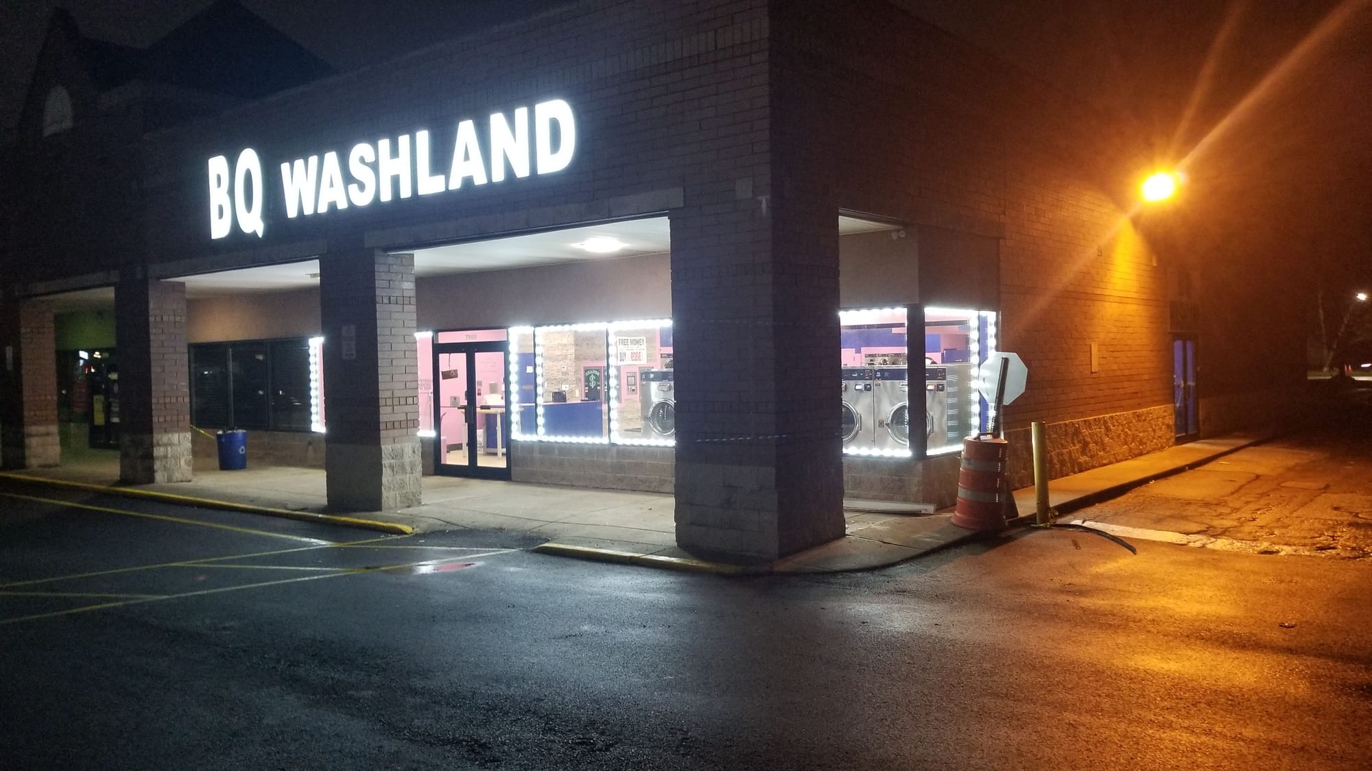 Lit BQ WASHLAND letters and LED outlined windows on a corner laundromat at night