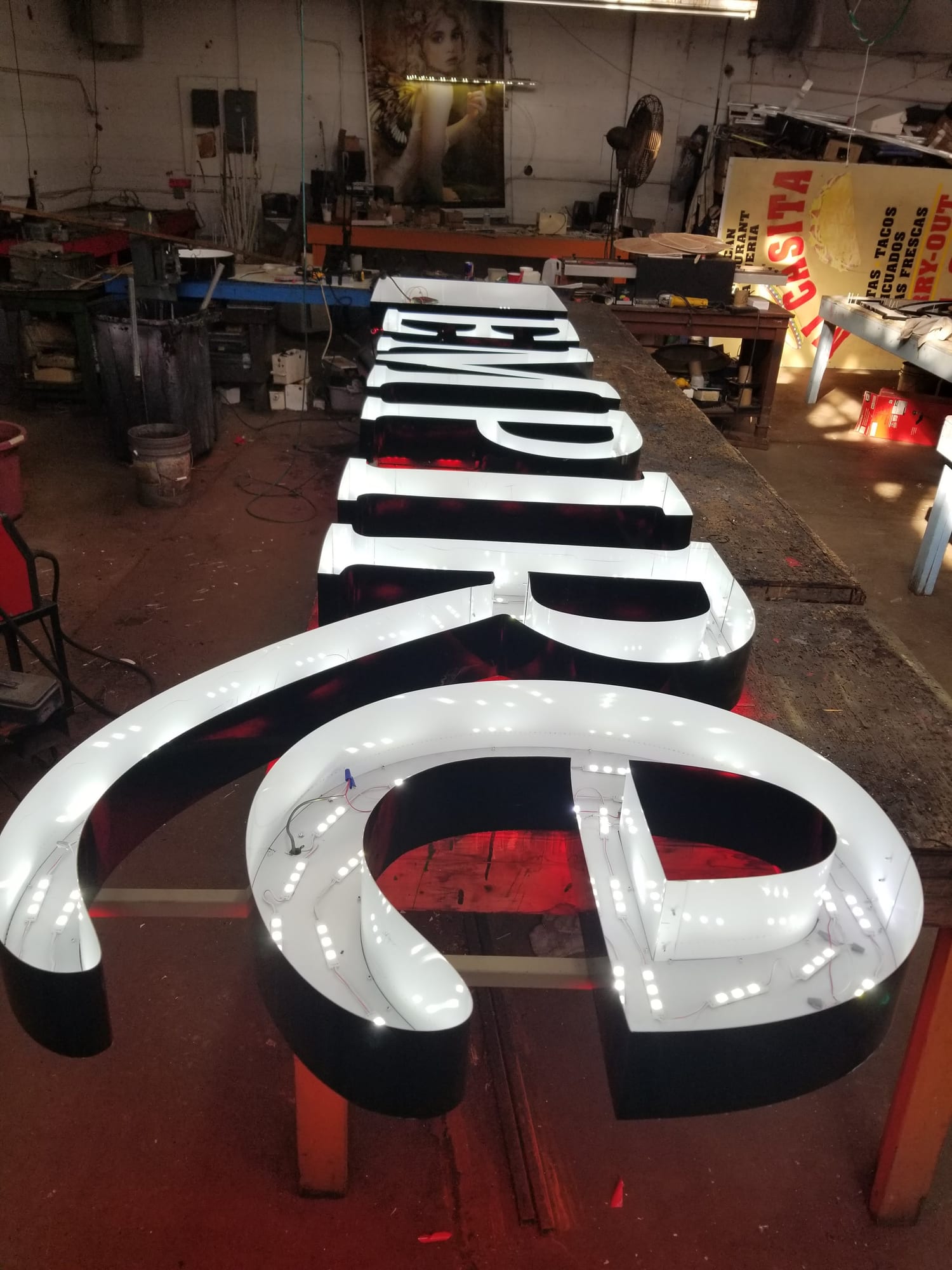 Lit EMPIRE channel letters with LED modules lined up along a shop bench