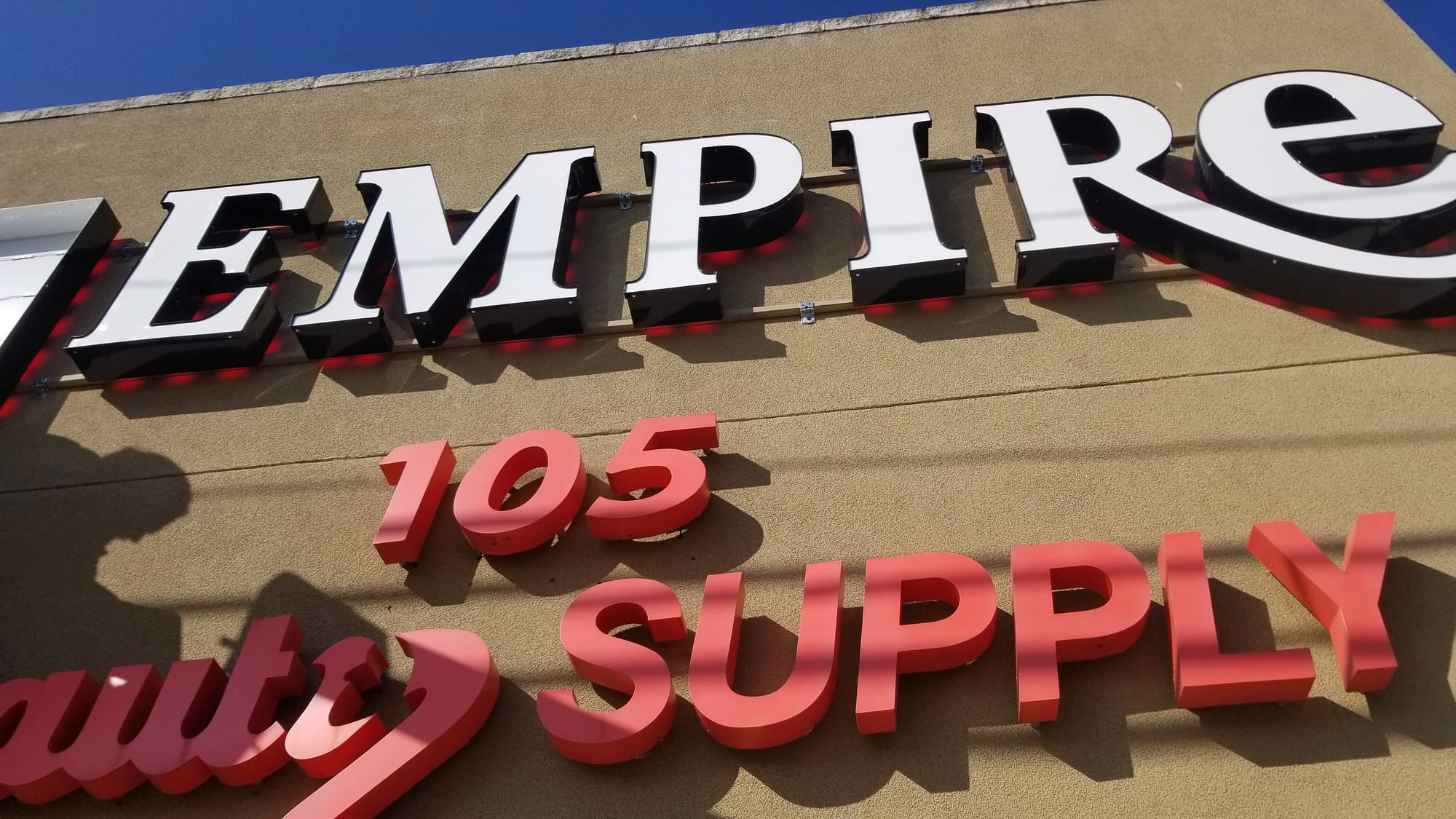 Close view of EMPIRE channel letters with red halo LEDs and red SUPPLY letters below