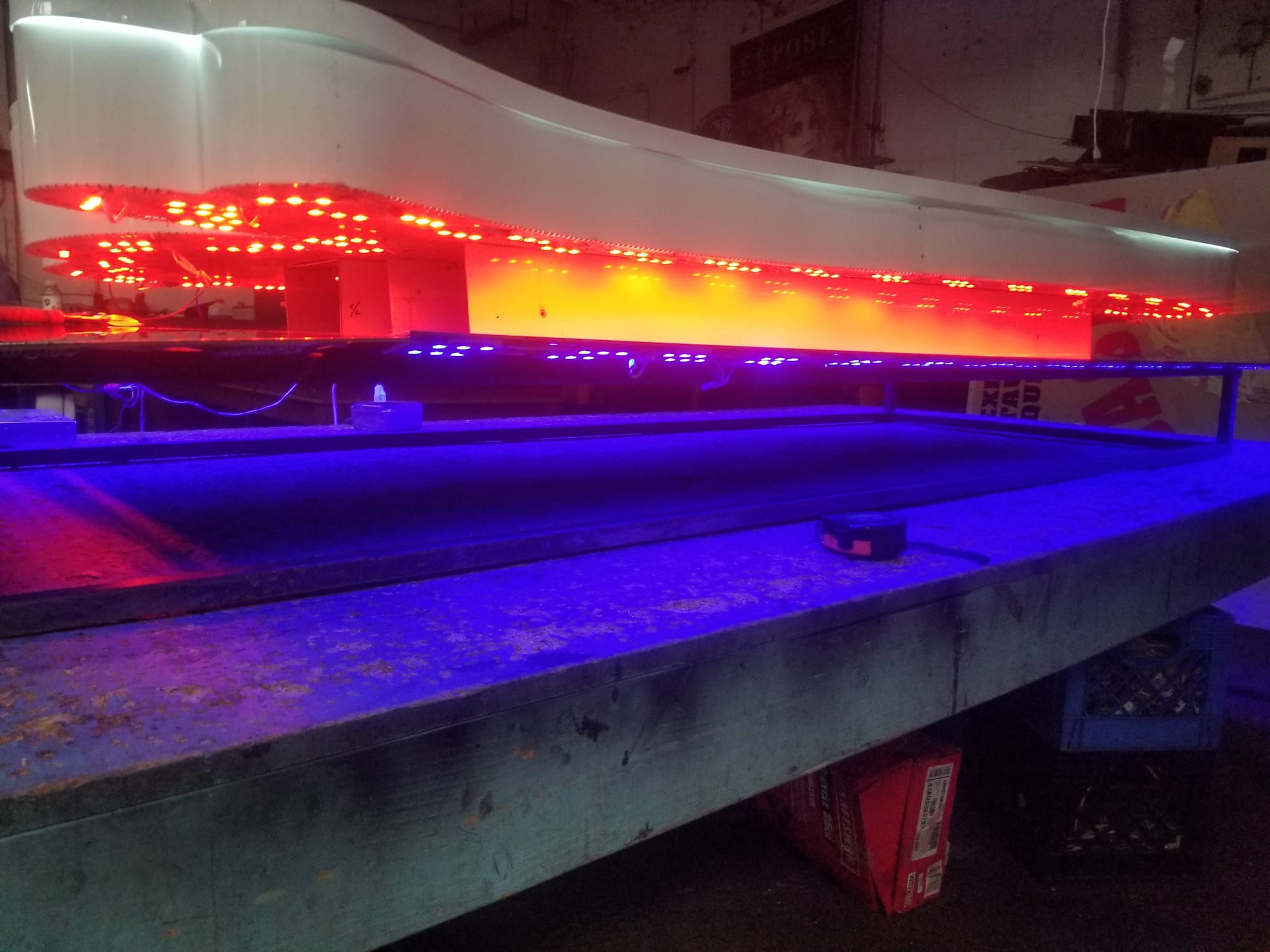 Edge view of a lit sign cabinet with red and blue LEDs glowing on a shop table