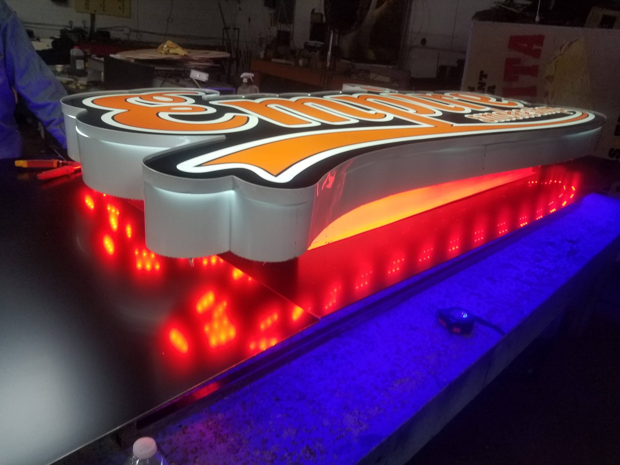 Angled view of the lit Empire cabinet sign showing white returns and red LEDs