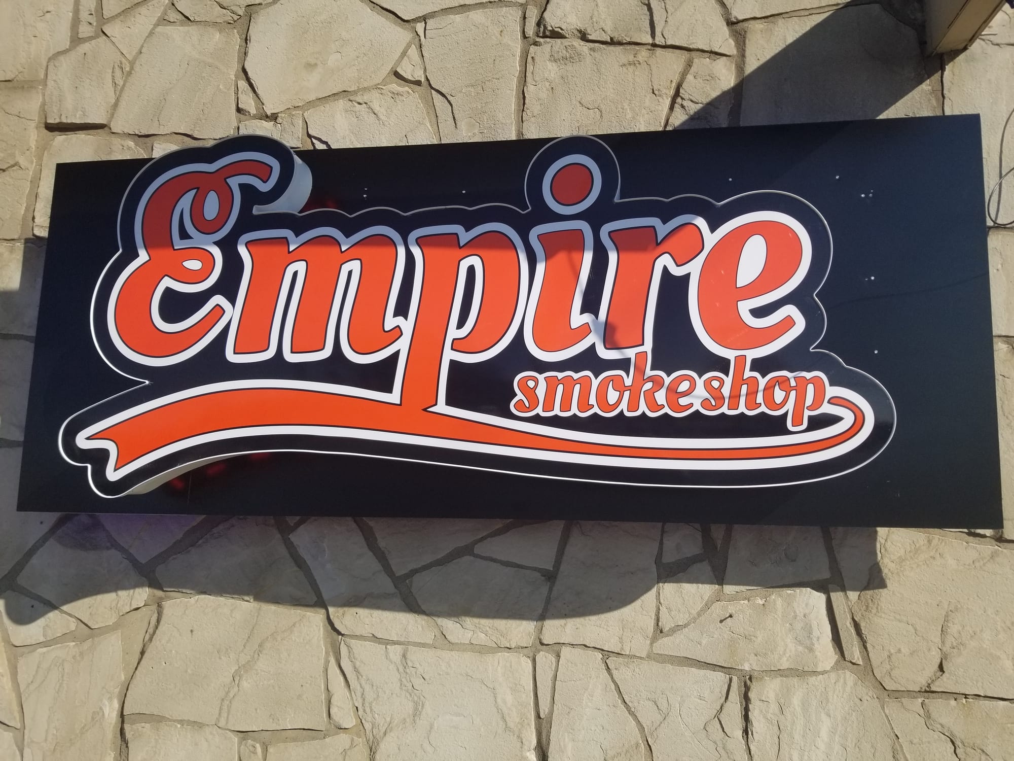 Close-up of the Empire Smokeshop lightbox cabinet sign on a stone wall