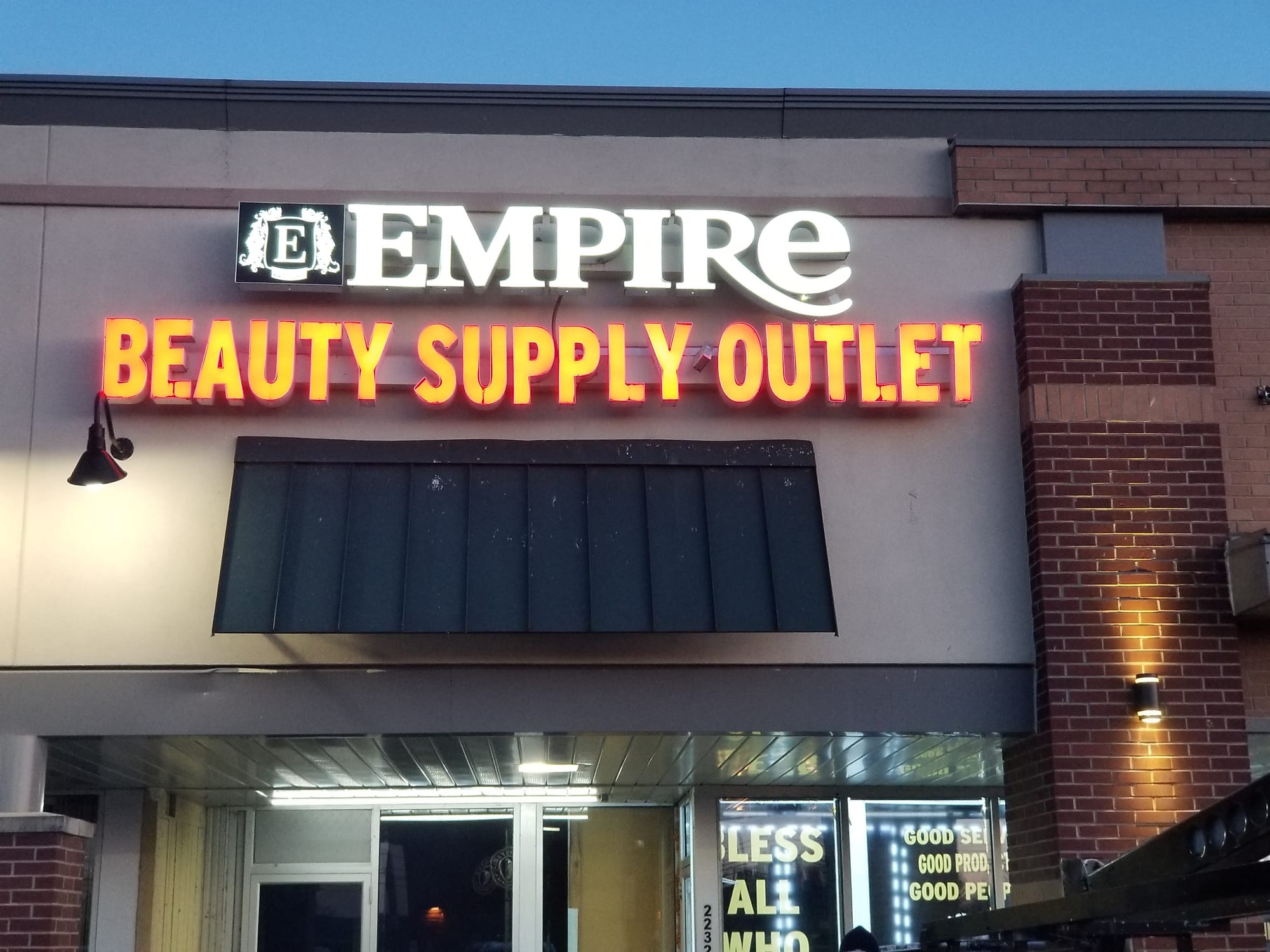 Empire Beauty Supply Outlet illuminated letters glowing above a storefront at dusk