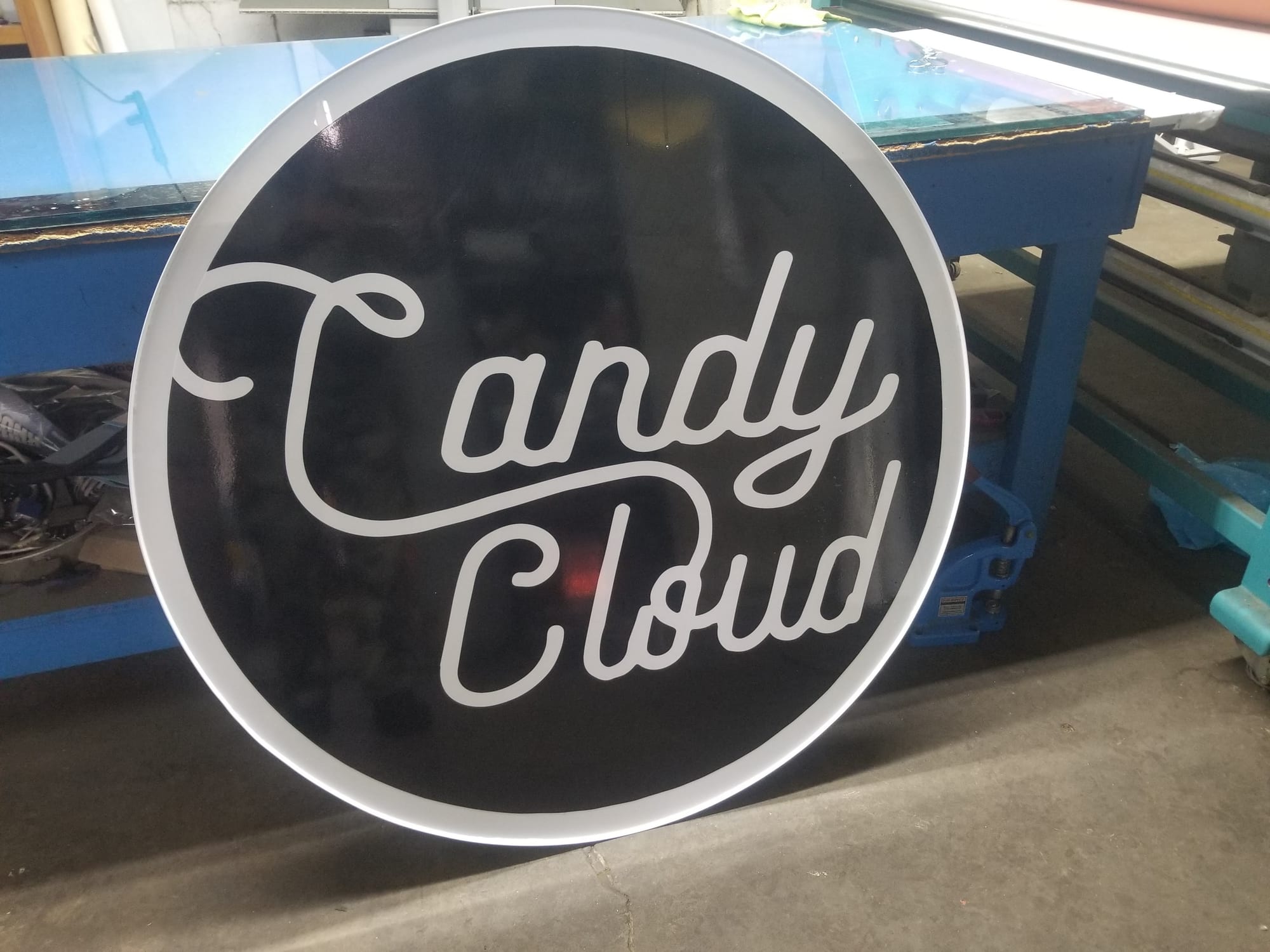Round Candy Cloud sign face leaning against a workbench in the shop