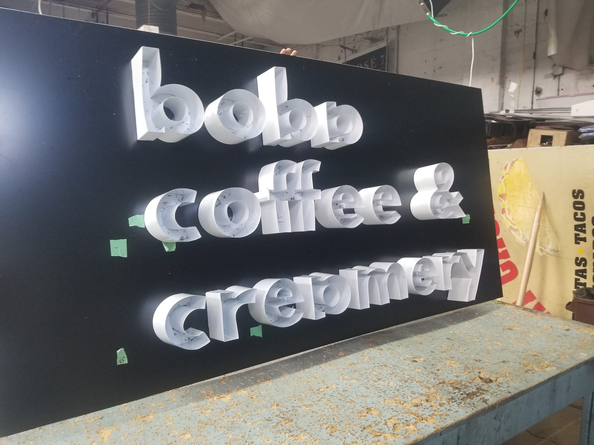 White channel letters spelling boba coffee and creamery set on a black panel in the shop