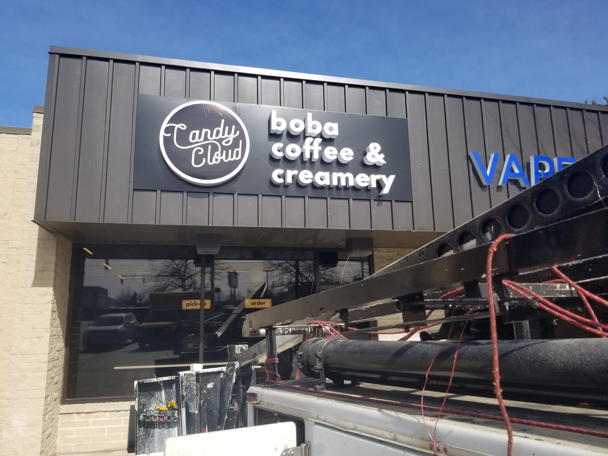 Candy Cloud boba coffee and creamery sign on a storefront with a truck boom in frame