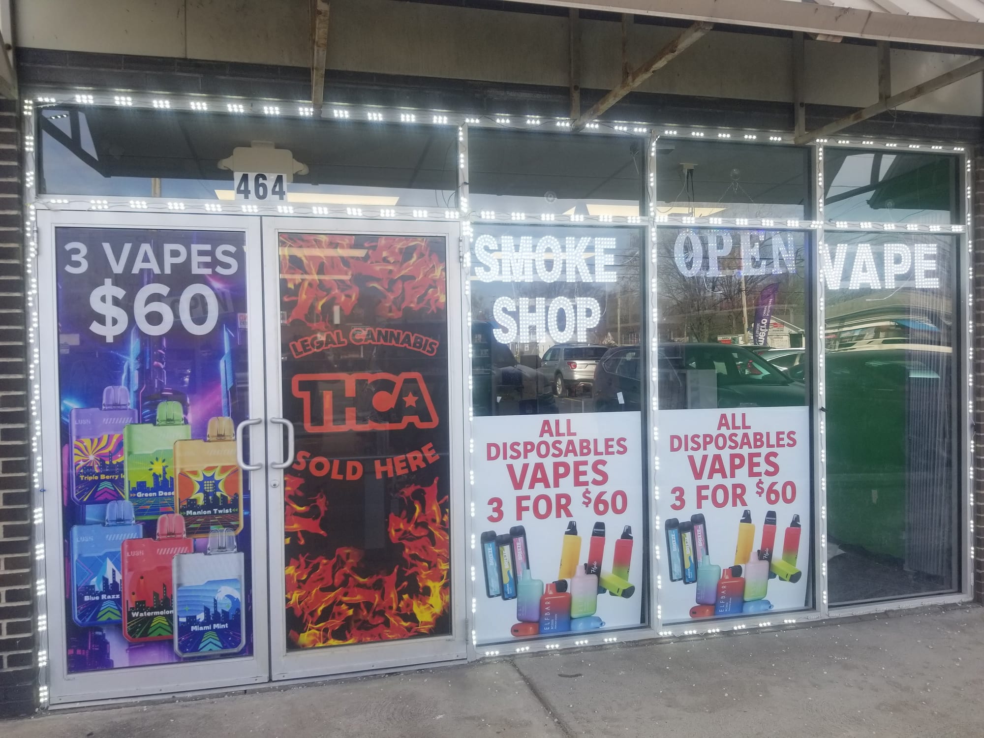 Printed window graphics and vinyl lettering across a smoke shop storefront glass
