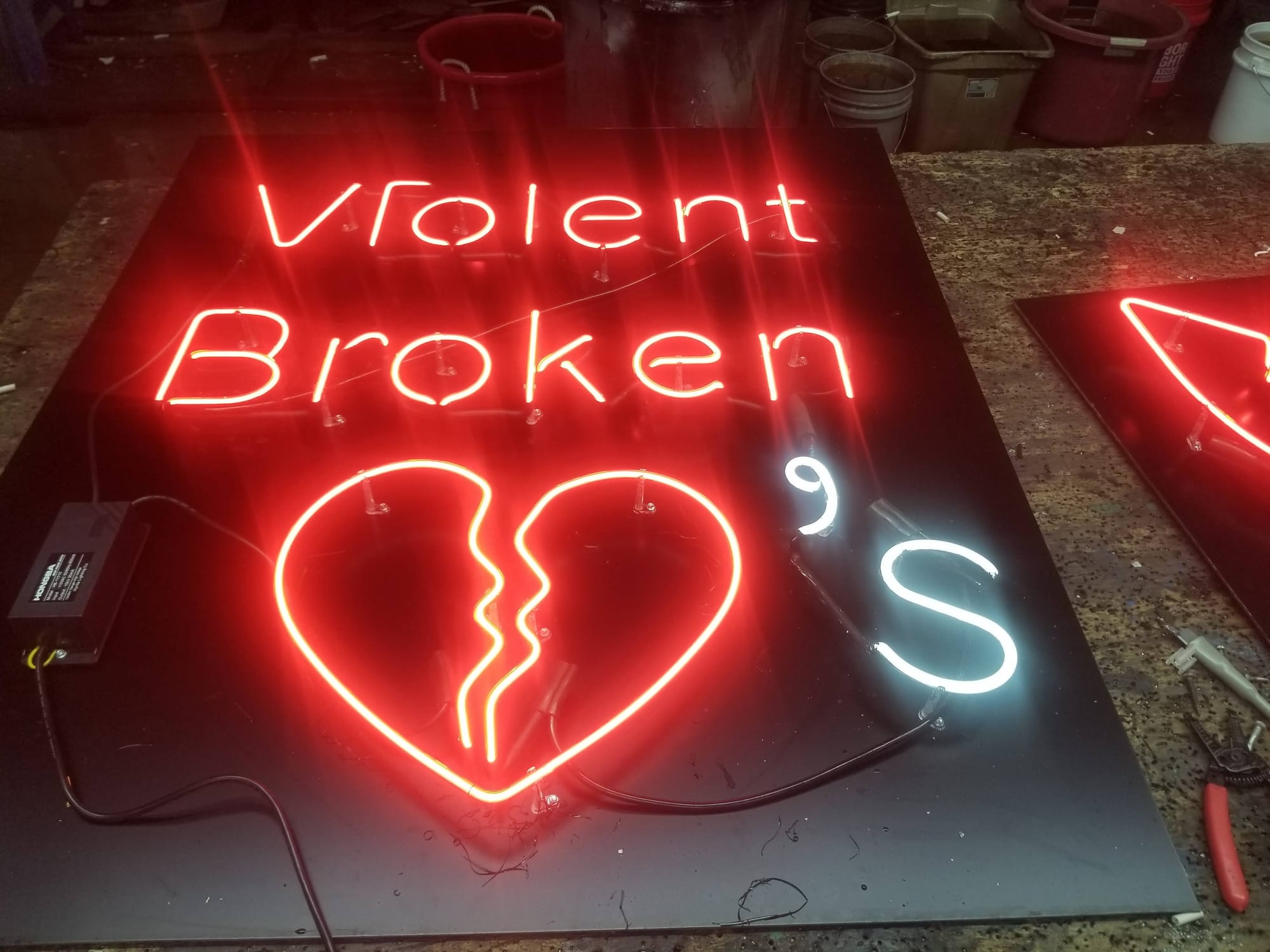 Violent Broken 90's neon sign with a broken heart glowing on a shop bench