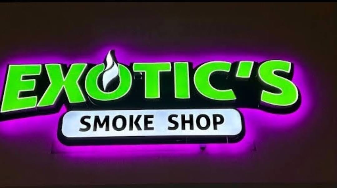 Exotic's Smoke Shop halo-lit letters glowing purple against a dark wall