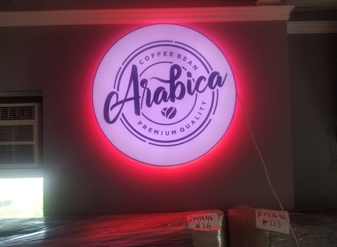 Round Arabica logo lightbox with red halo glow mounted on an interior wall