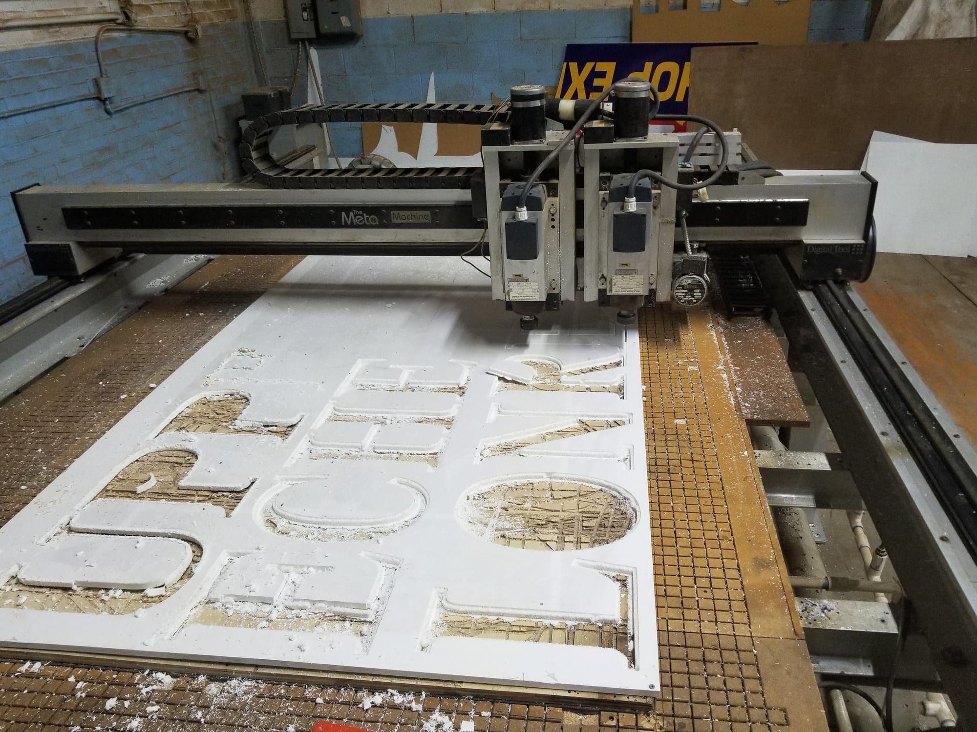 CNC router table cutting sign lettering out of a large white panel in the shop