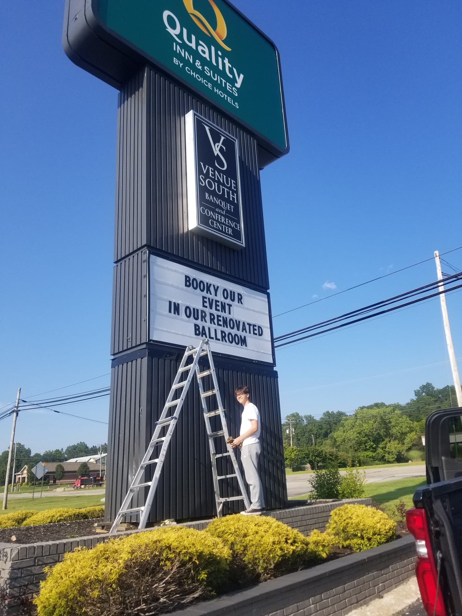 Worker with a stepladder at the base of the Quality Inn & Suites pylon sign