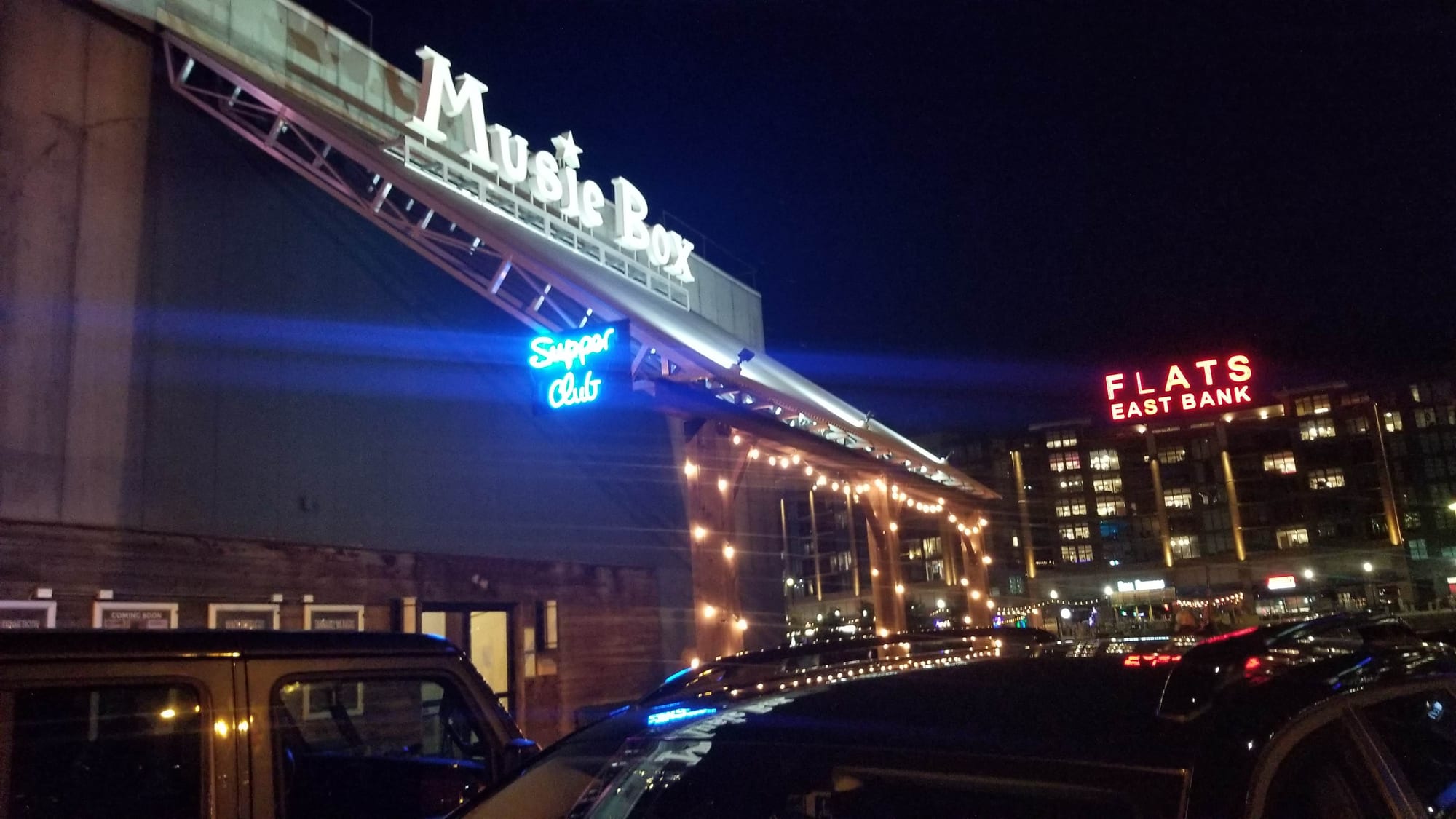 Lit Music Box letters on a rooftop frame with the blue neon Supper Club sign below