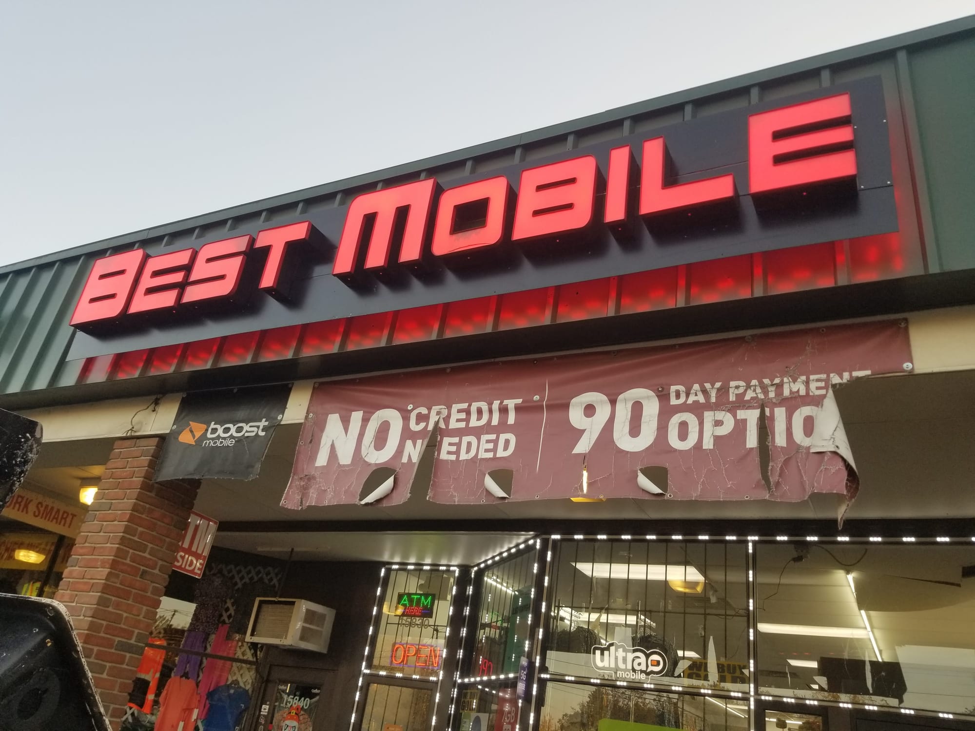 Red illuminated BEST MOBILE channel letters on a raceway above a storefront at dusk