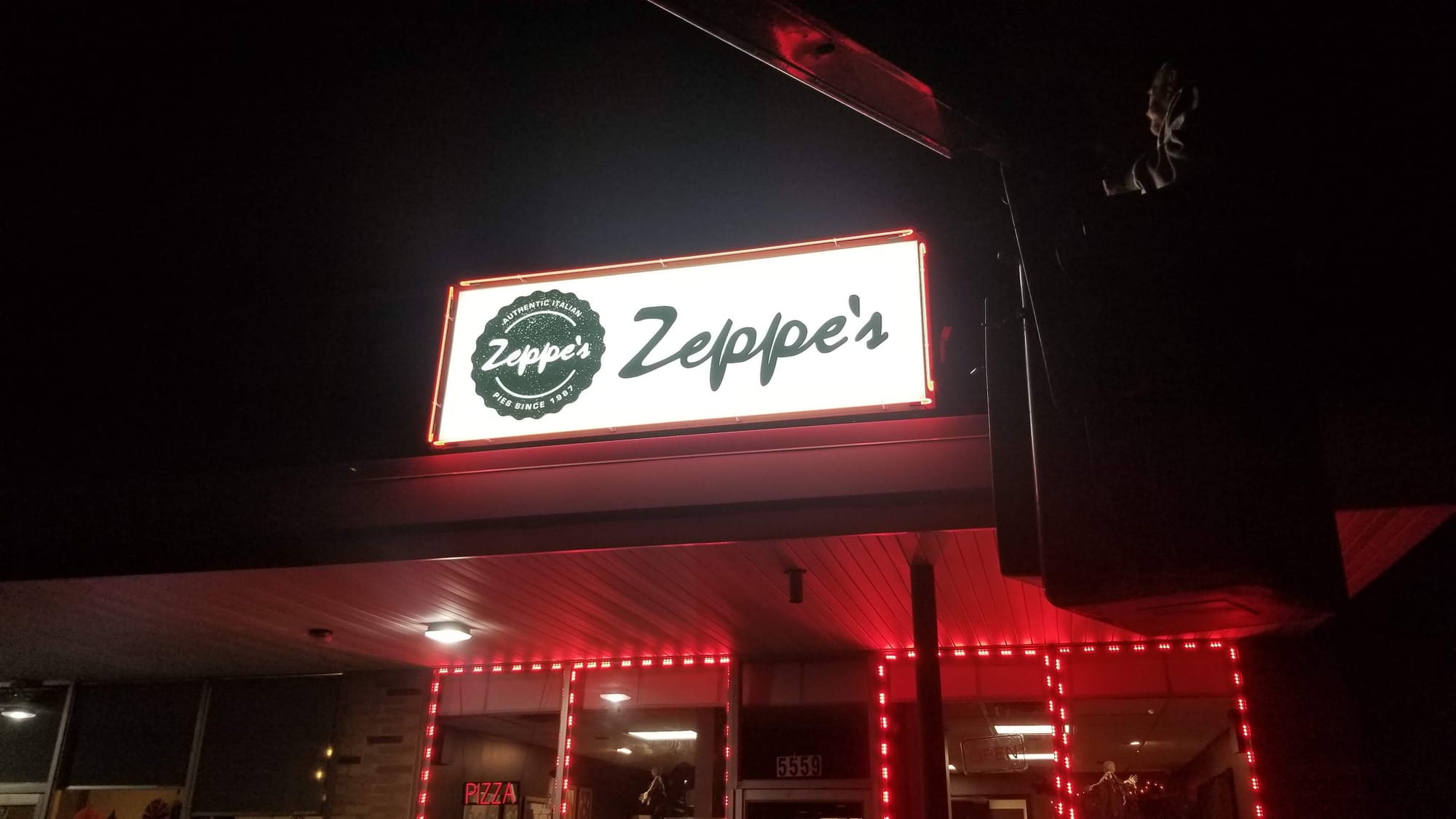 Lit Zeppe's cabinet sign with a red neon border above a storefront entrance at night