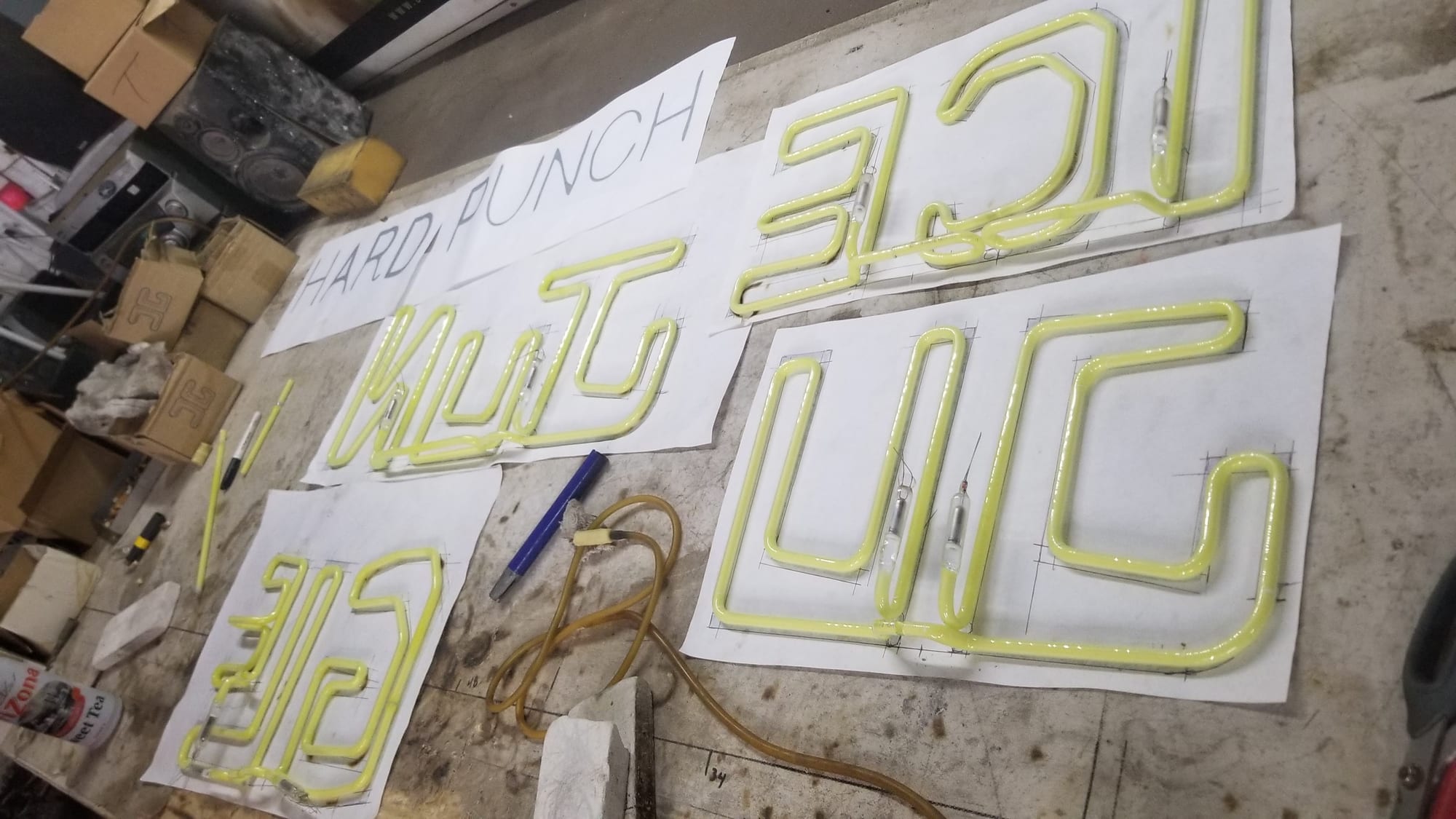 Yellow neon letter tubes laid out on paper layout patterns on the neon bench