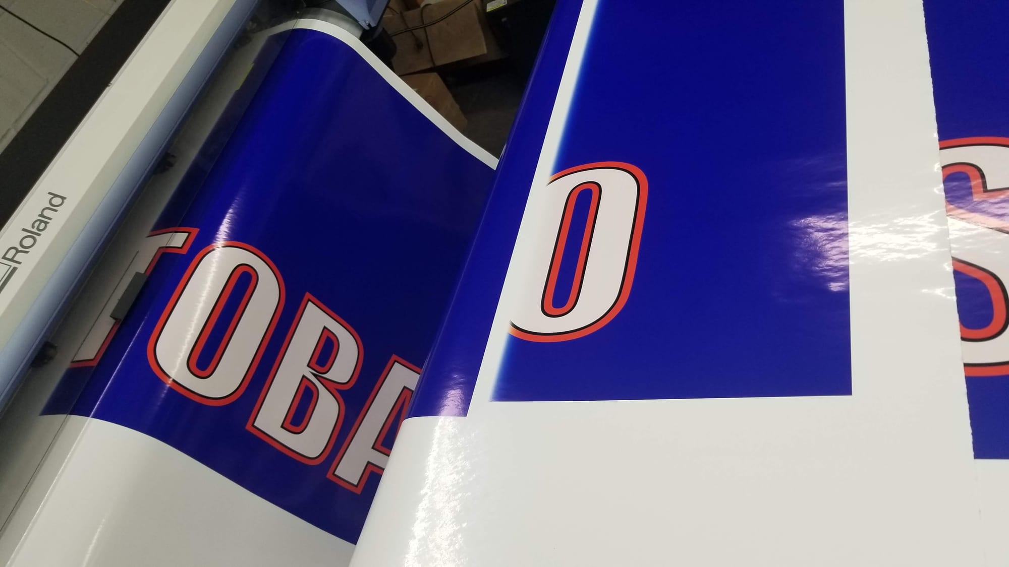 Close-up of blue printed vinyl banner material on a Roland wide format printer