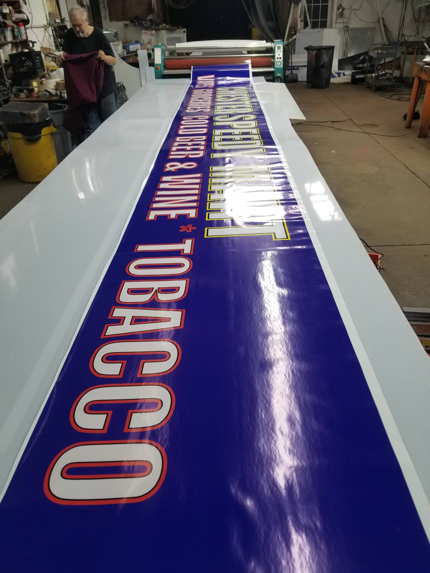 Long printed CHESTER SPEEDY MART vinyl banner laid out across a shop table