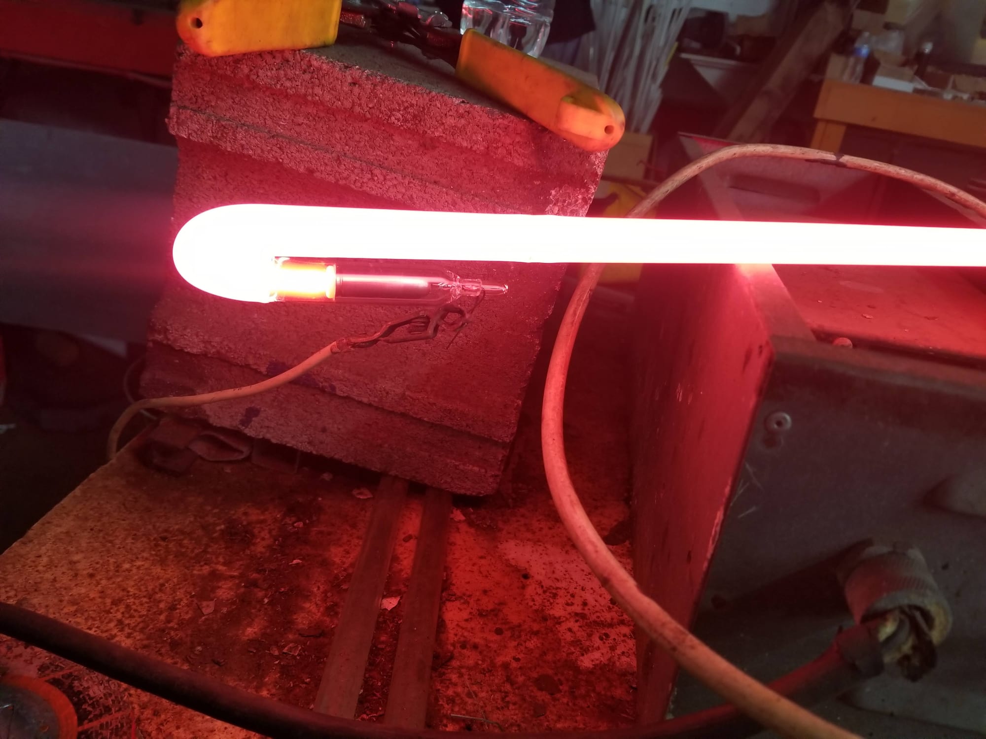 Glowing red neon tube resting on firebrick at the bending bench