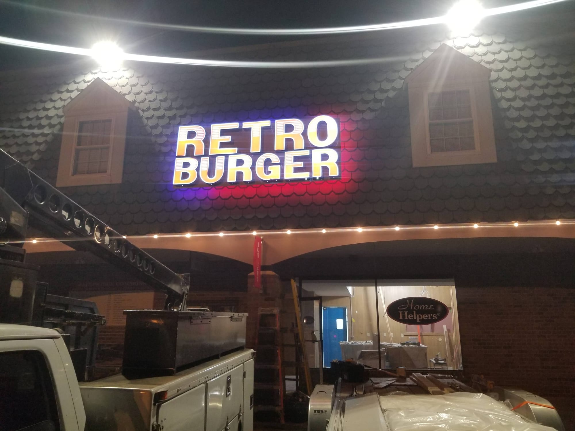 Illuminated RETRO BURGER sign mounted on a shingled facade at night