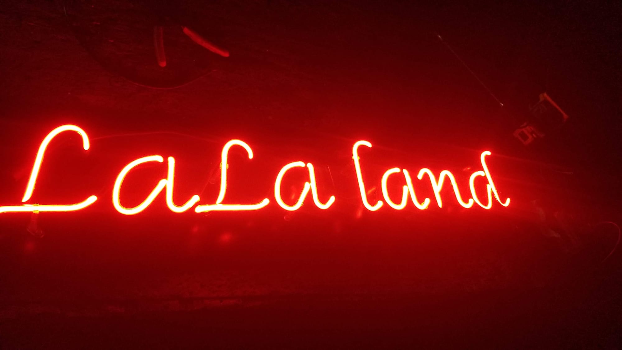 Red neon LaLa land script sign glowing in a dark shop