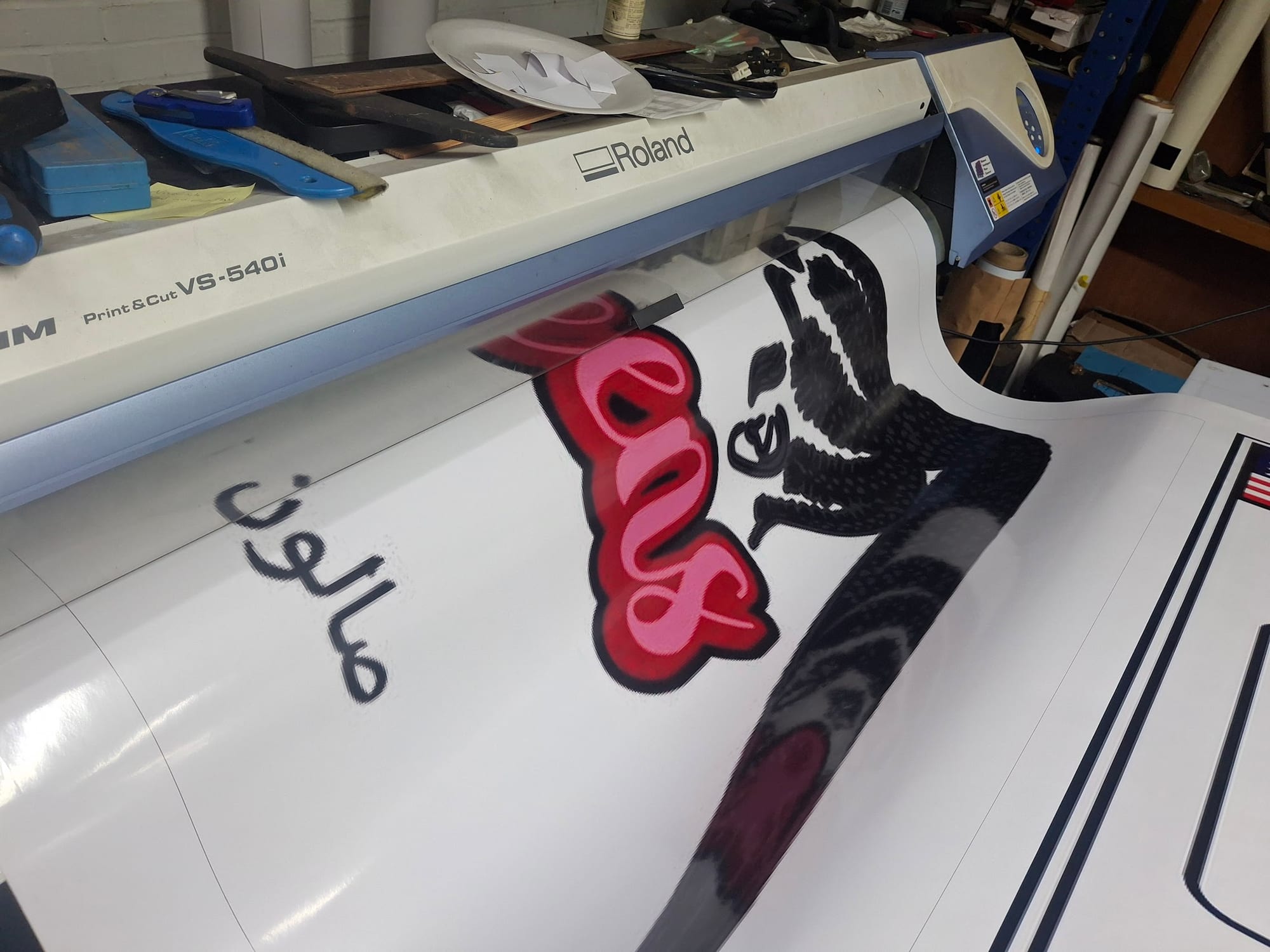 Roland VS-540i print and cut machine in the shop with printed vinyl graphics on the roll