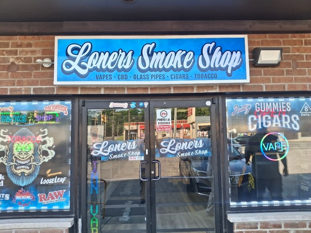 Loners Smoke Shop lightbox sign above a storefront with matching window decals