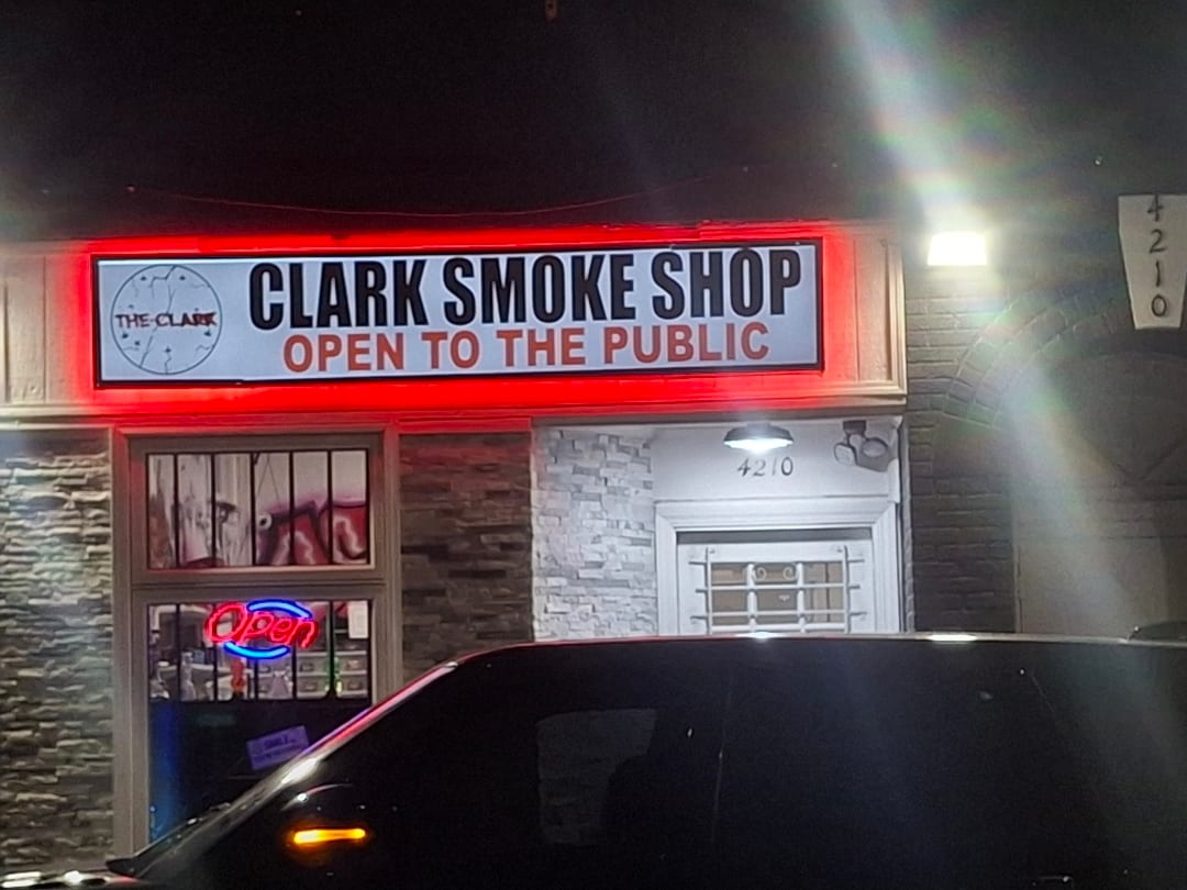 Clark Smoke Shop lightbox sign with red halo glow above the storefront at night