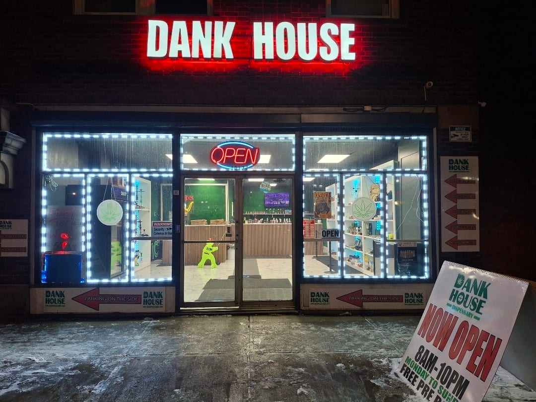 DANK HOUSE channel letters glowing white with red halo above a storefront at night