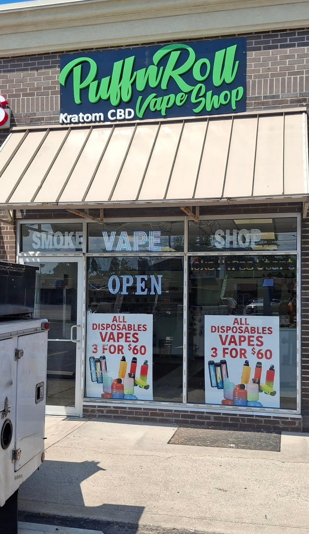 PuffnRoll Vape Shop sign panel above the awning with window posters below