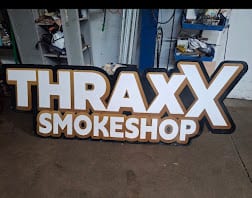 THRAXX SMOKESHOP letters on a black backer panel standing in the fabrication shop