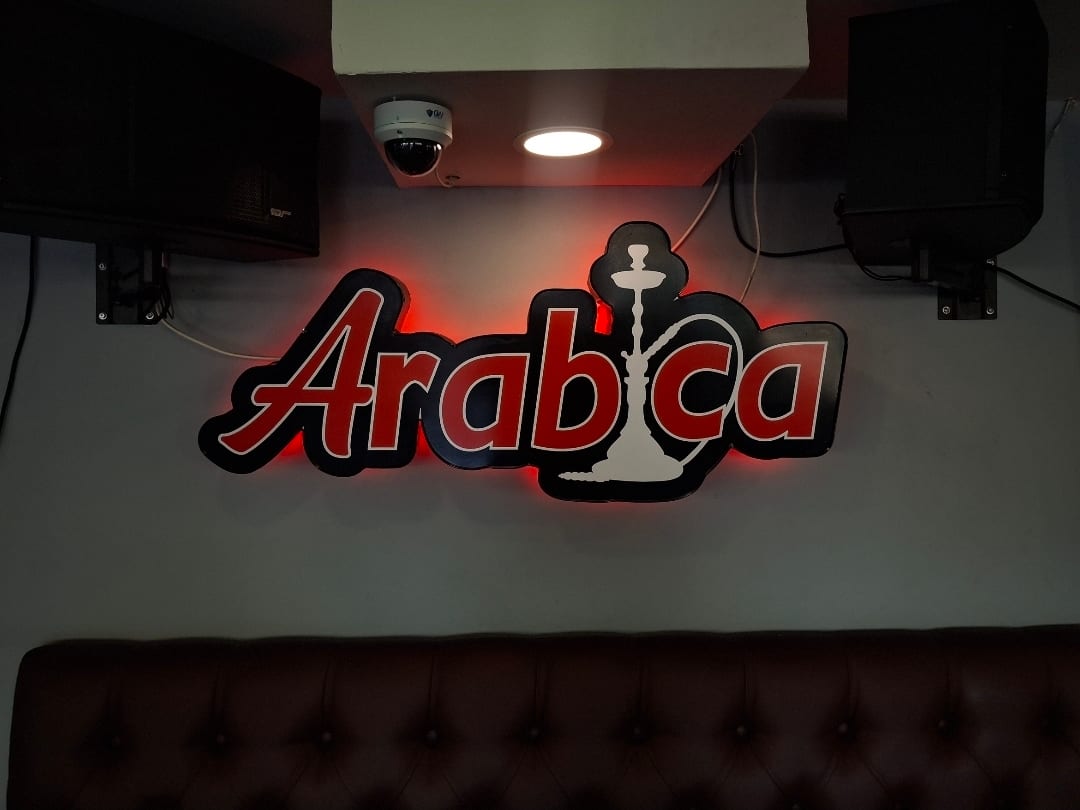 Arabica halo-lit logo sign with hookah graphic glowing red on an interior wall