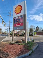 Shell branded pylon sign with an LED fuel price display beside a road