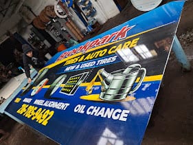 Large blue printed auto care banner with tires and oil change graphics laid out in the shop