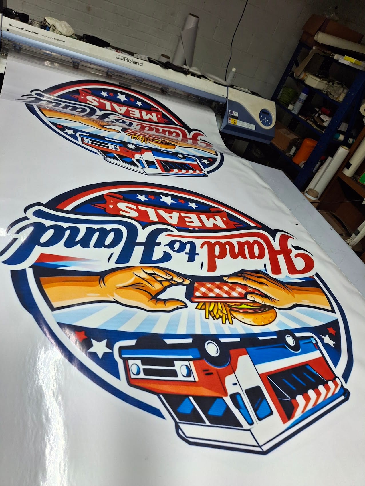 Printed Hand to Hand Meals decals coming off the wide format printer in the shop