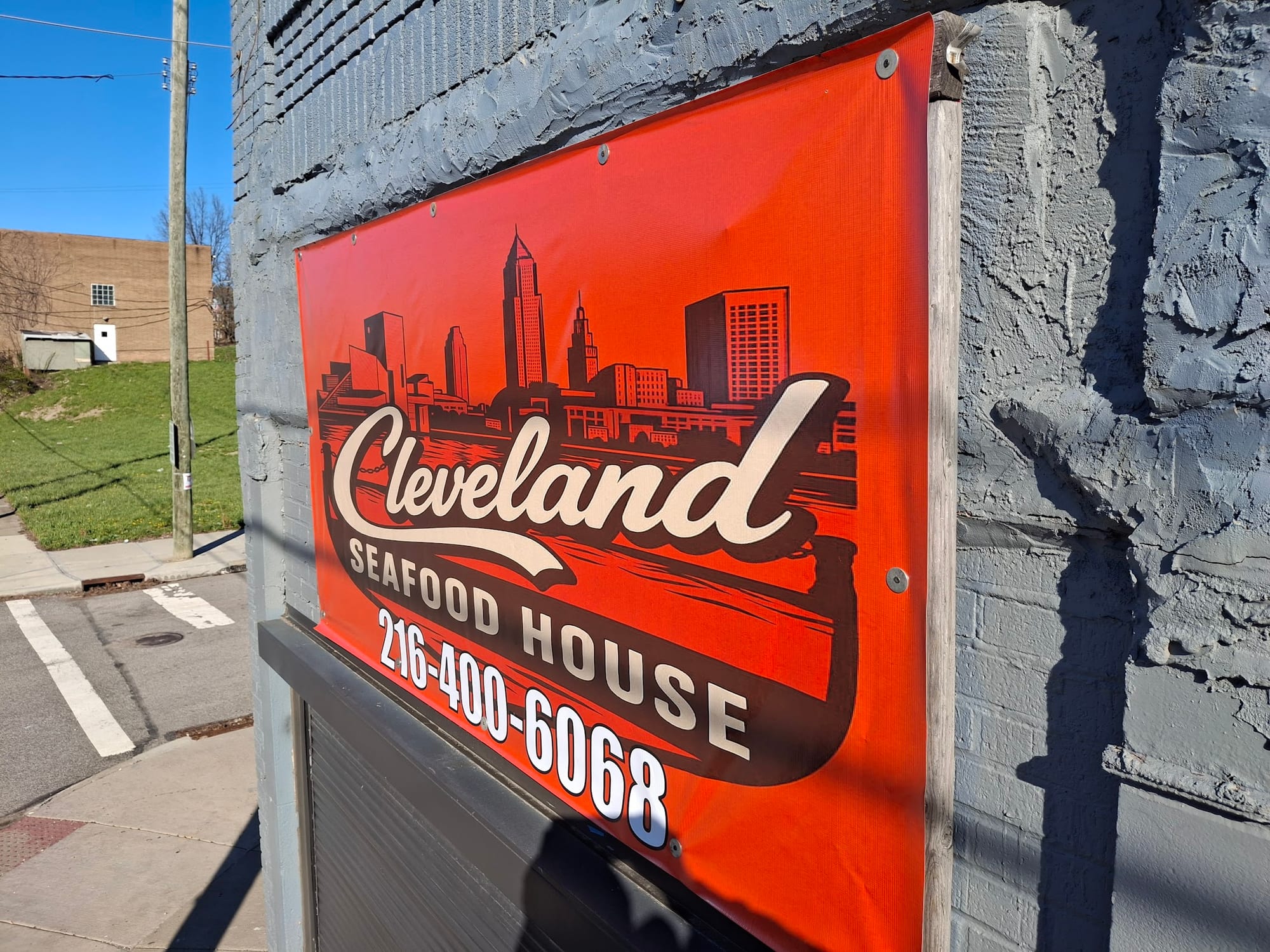 Orange Cleveland Seafood House banner mounted on a grey brick wall