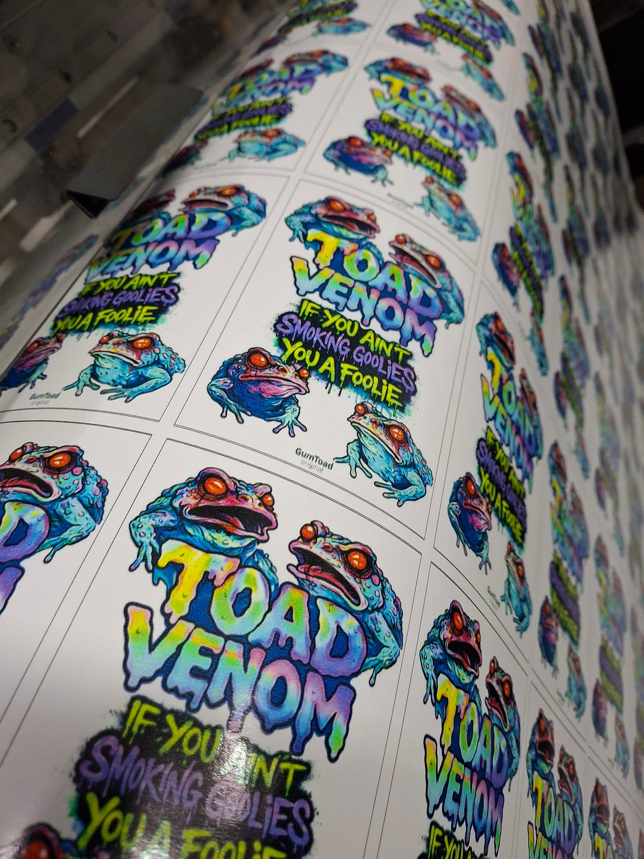 Sheet of printed Toad Venom vinyl stickers coming off a wide-format printer