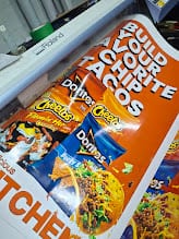 Close crop of a printed nacho promotion graphic showing bags of Cheetos
